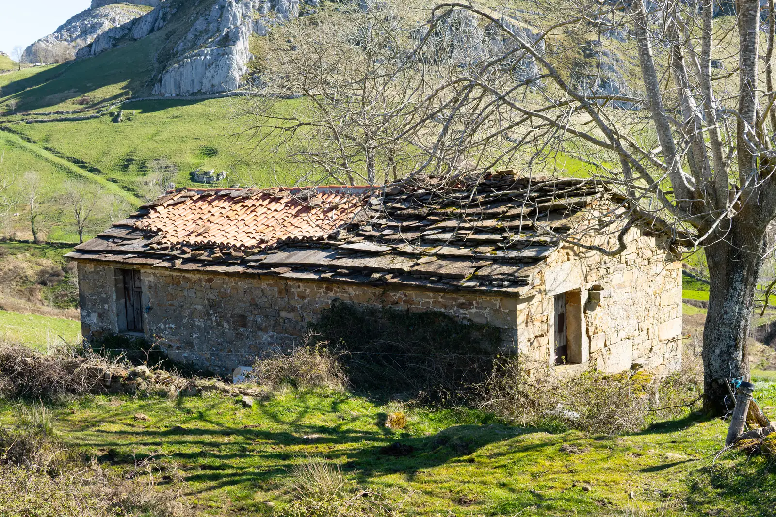 Casa antigua de piedra con tejado de pizarra pendiente de rehabilitar en un pueblo de montaña