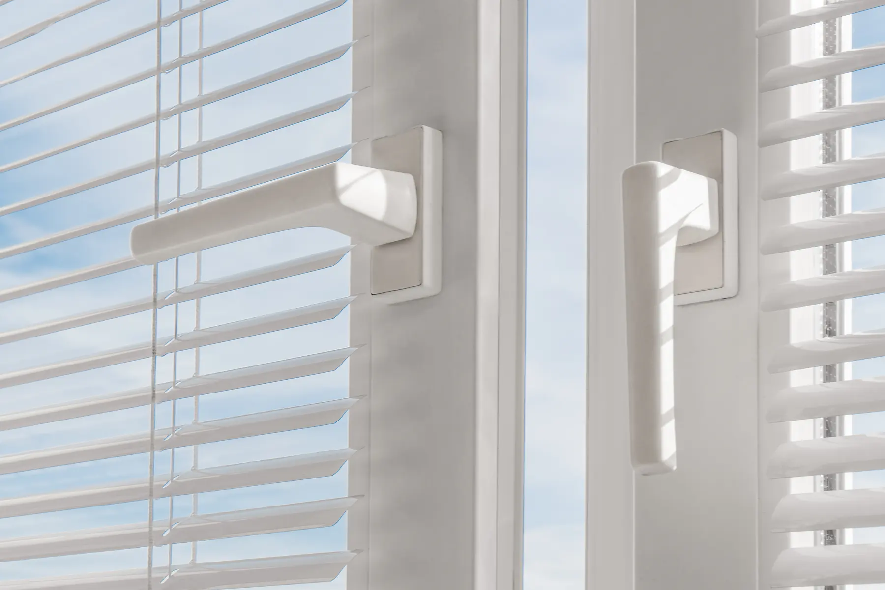 Venecianas blancas en una ventana con vistas a la ciudad